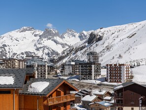 A mountain resort with wooden buildings and modern apartments, featuring snow-covered peaks in the background. - Comfortable studio with balcony in Tignes Le Lac for 4 people (Tignes)