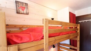 A bunk bed with red bedding in a room with wooden walls and a door with red curtains. - Comfortable studio with balcony in Tignes Le Lac for 4 people (Tignes)