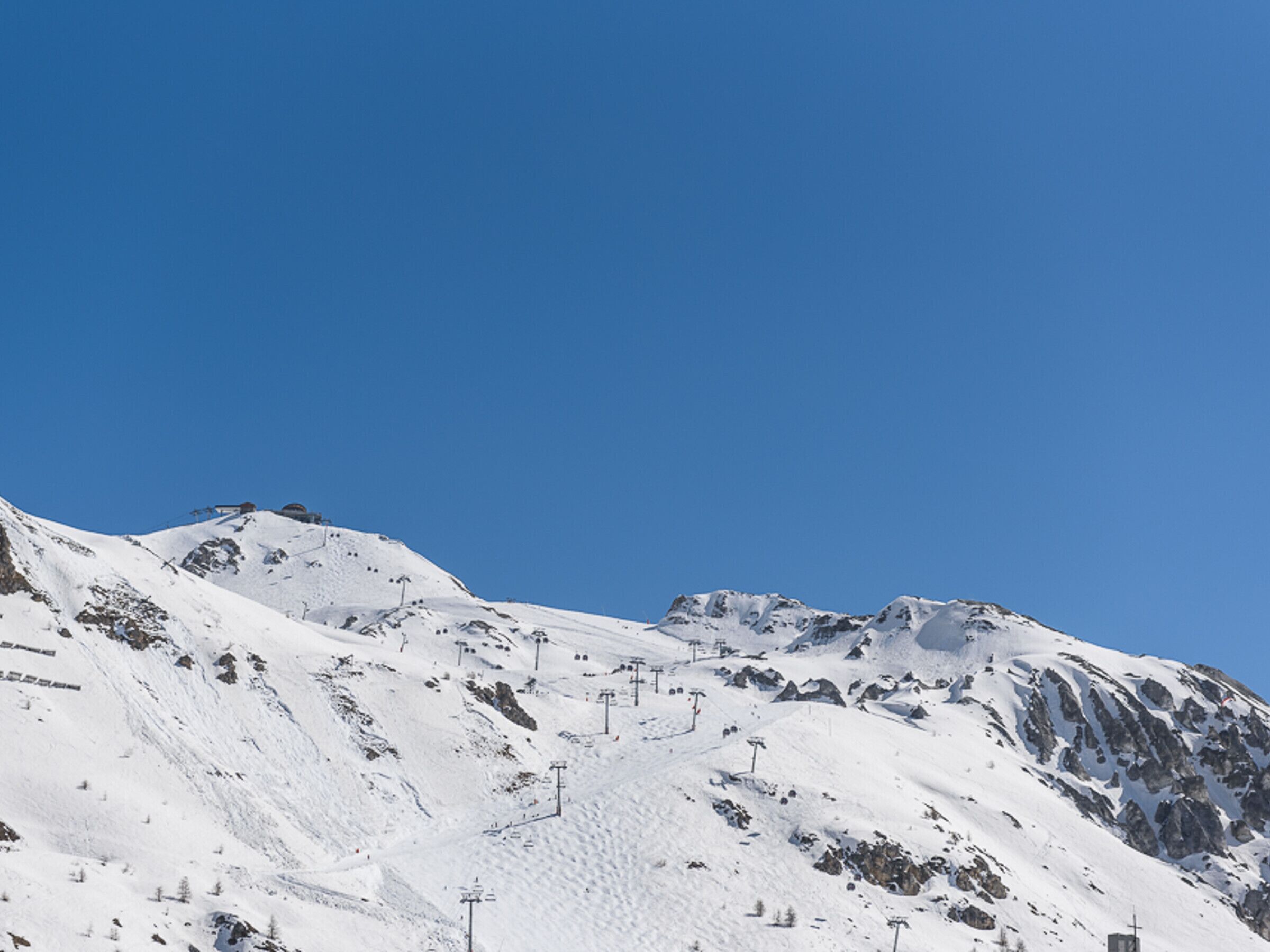 Pendiente nevada de una montaña con telesillas y un cielo azul despejado.