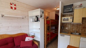 A compact room with a bunk bed, a kitchenette, and a sofa with red cushions. - Comfortable studio with balcony in Tignes Le Lac for 4 people (Tignes)