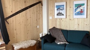 Une pièce aux murs lambrissés, avec un canapé, un banc et deux tableaux encadrés.