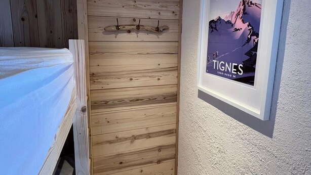 Une chambre avec un mur recouvert de lambris en bois, un lit et une affiche encadrée accrochée au mur.