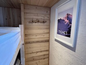 A bedroom with a wooden slat wall, a bed, and a framed poster on the wall. - Renovated studio in Tignes, near slopes, balcony, pets allowed (Tignes)