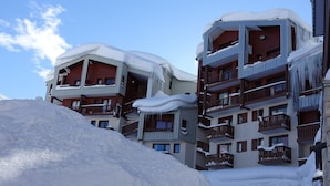 Un hôtel à plusieurs étages, doté de balcons couverts de neige, se dressant sur un ciel dégagé.