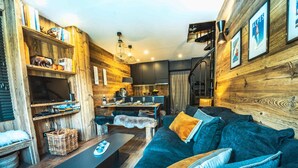 Un salon confortable avec un canapé, une table basse et un téléviseur. Il y a également un coin cuisine avec une table à manger et des chaises.