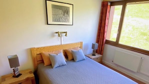 A bedroom with a bed, nightstands, a lamp, a framed picture, and a window with curtains. - Beautiful apartment for 7, balcony, direct slope access (Tignes)