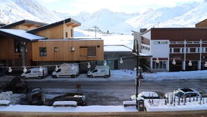 A snowy mountain town with wooden buildings, a parking lot, and a snow-covered street.