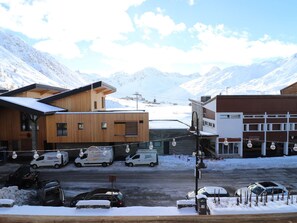 A snowy mountain town with wooden buildings, a parking lot, and a snow-covered street.