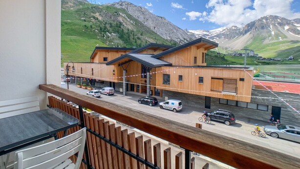 A modern building with a wooden facade, a covered entrance, and a view of a mountainous landscape.