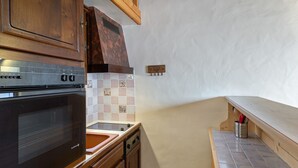 A kitchen with wooden cabinets, a black oven, a tiled backsplash, and a wooden countertop.