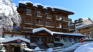 A multi-story wooden building with balconies, a covered entrance, and a sign for 'Sport 2000'.