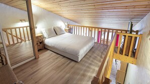 A bedroom with a wooden ceiling, a bed, a nightstand, and a window.