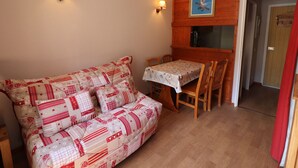 Une pièce chaleureuse avec un canapé, une table et des chaises, des murs en bois et une porte.