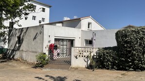 A modern two-story house with a concrete facade, a small balcony with a metal railing, and a potted plant in the foreground. - Villa Oceane 4 Chambres (San-Nicolao)