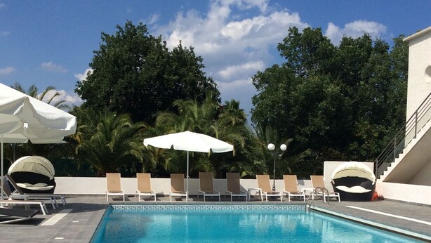 A rectangular swimming pool with clear blue water, surrounded by lounge chairs and white umbrellas. - Villa Oceane 4 Chambres (San-Nicolao)
