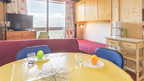 Ein gemütliches Zimmer mit einem Bett, einem Esstisch mit Obstplatte, einer Kaffeemaschine und einem Fernseher auf einer Holzkommode.