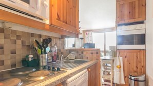 Eine Küche mit Holzausstattung, einer Granit-Arbeitsplatte, einem Geschirrspüler und einem Edelstahl-Mülleimer.