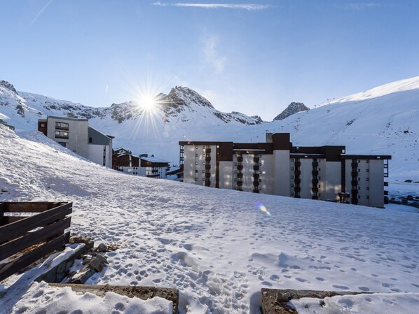 A snow-covered mountain area with modern buildings, including a hotel with multiple floors and balconies.