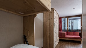 Ein Schlafzimmer mit einem hölzernen Bett, einer roten Couch und einem großen Fenster.