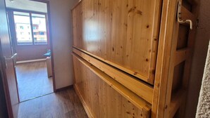 A room with wooden cabinets, a window, and a door leading to another room.