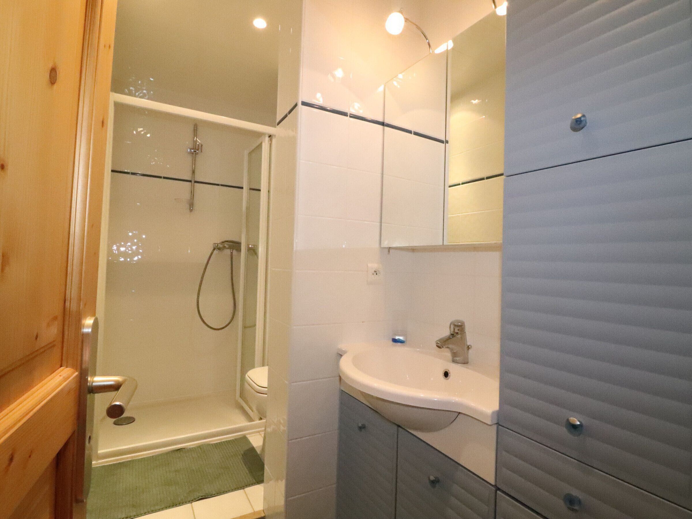 A bathroom with a glass-enclosed shower, a toilet, a sink, and a mirror.