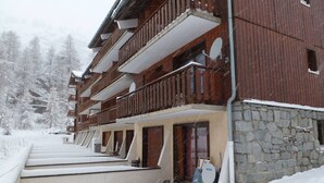 A multi-story wooden building with balconies, a stone foundation, and a snowy landscape. - Renovated studio with balcony, near slopes, pets allowed (Tignes)