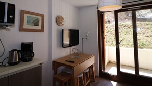 A small kitchen with a wooden table, a kettle, a coffee maker, a TV, and a pendant light. - Renovated studio with balcony, near slopes, pets allowed (Tignes)