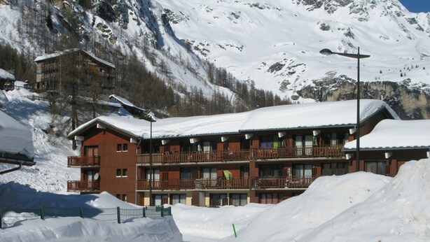 A multi-story hotel with balconies, surrounded by snow-covered mountains. - Renovated studio with balcony, near slopes, pets allowed (Tignes)