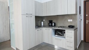 A compact kitchen with light wood cabinets, a built-in microwave, and a coffee maker. - Beautiful Apt. close to Monastiraki (Athens)