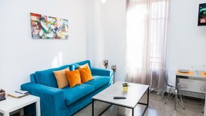 A modern living room with a blue sofa, a coffee table, and a painting on the wall. - Beautiful Apt. close to Monastiraki (Athens)