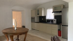 Eine Küche mit einem runden Holztisch, beigen Schränken, einer Mikrowelle und einem Kühlschrank.