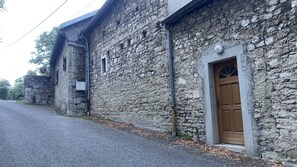 Un bâtiment en pierre avec une porte en bois, une petite fenêtre et une antenne parabolique.