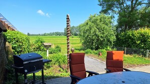 Eine Terrassenanlage im Freien mit Grill, zwei Stühlen und einem Tisch.