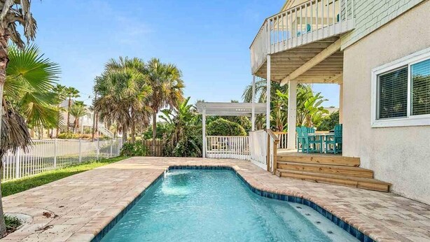 A swimming pool with a wooden deck and a covered patio area.