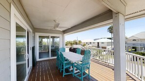 A covered outdoor area with a table and chairs, a ceiling fan, and a view of neighboring houses.