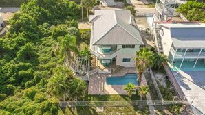 A residential property with a swimming pool, surrounded by lush greenery and a fenced yard.