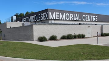 The exterior of the West Middlesex Memorial Centre, featuring a modern building with a flat roof, large windows, and a landscaped front yard with small bushes.
