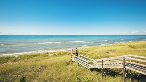 A wooden boardwalk leading to a beach with grassy dunes and a clear blue sky. - Holiday Inn Express Strathroy by IHG (Adelaide Metcalfe)