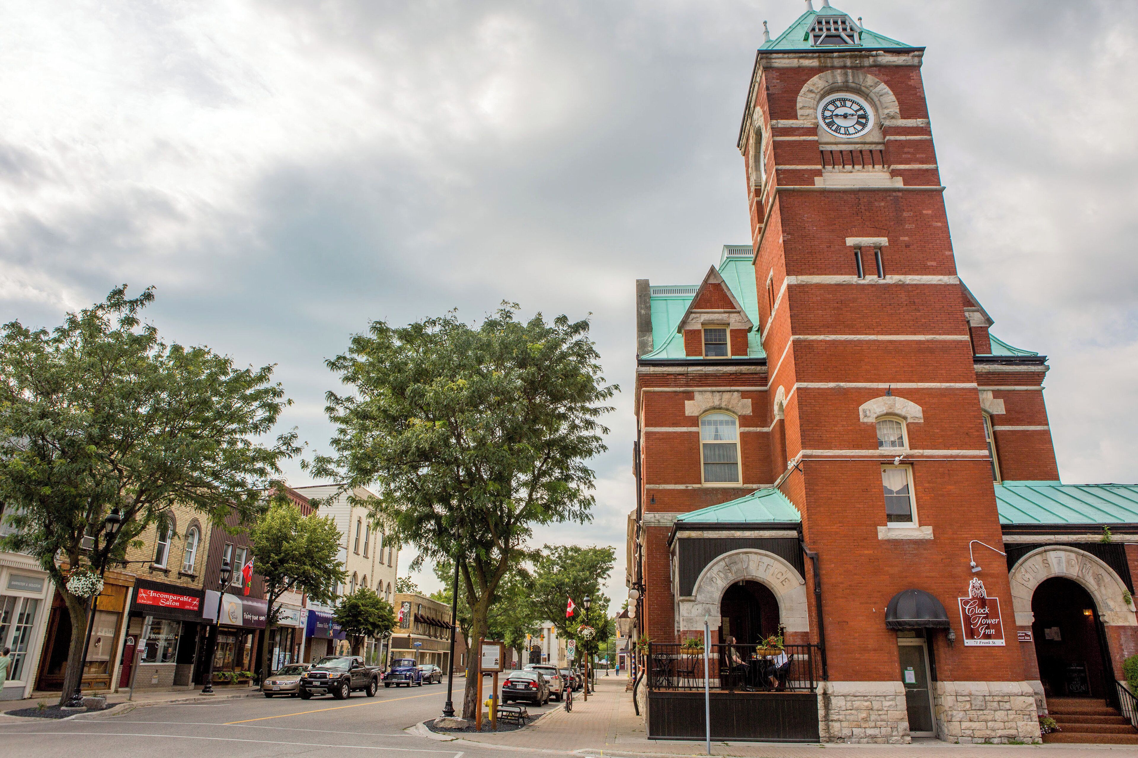 A historic brick building with a clock tower, arched windows, and a sign for the Clock Tower Inn.