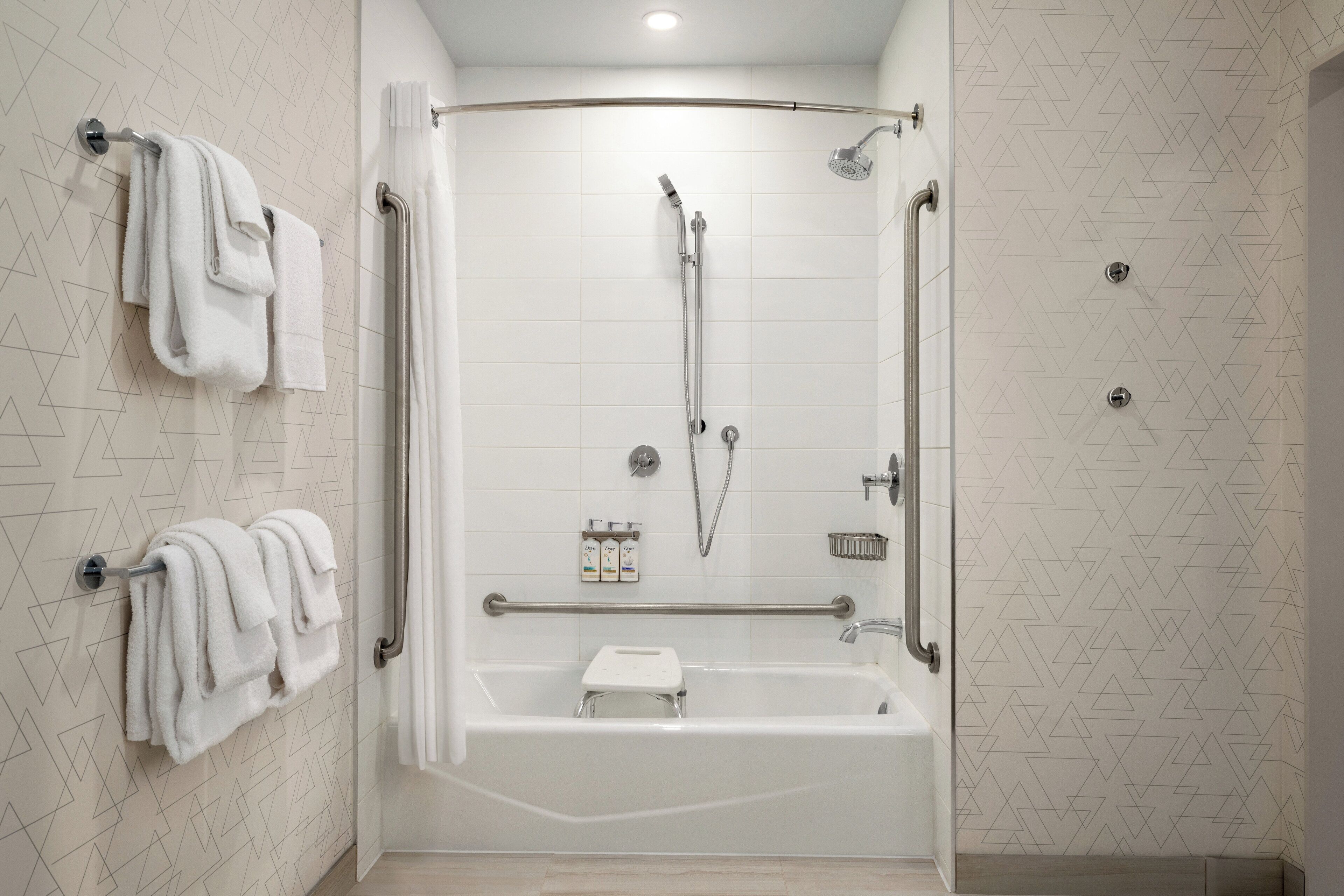 A modern bathroom with a walk-in shower, grab bars, and a towel rack.