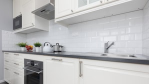Una cocina moderna con armarios blancos, un lavamanos de acero inoxidable y un horno empotrado.