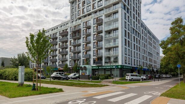 Un edificio residencial de varios pisos con balcones, una tienda de mascotas y un carril bici.