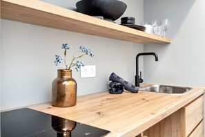 A kitchen with a wooden countertop, a black sink, and a vase with blue flowers.
