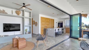 A modern living room with a flat-screen TV, wooden furniture, and a ceiling fan. - Belnem House Bonaire (Kralendijk)