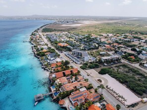 An aerial view of a coastal town with a beach, residential buildings, and a marina. - Belnem House Bonaire (Kralendijk)