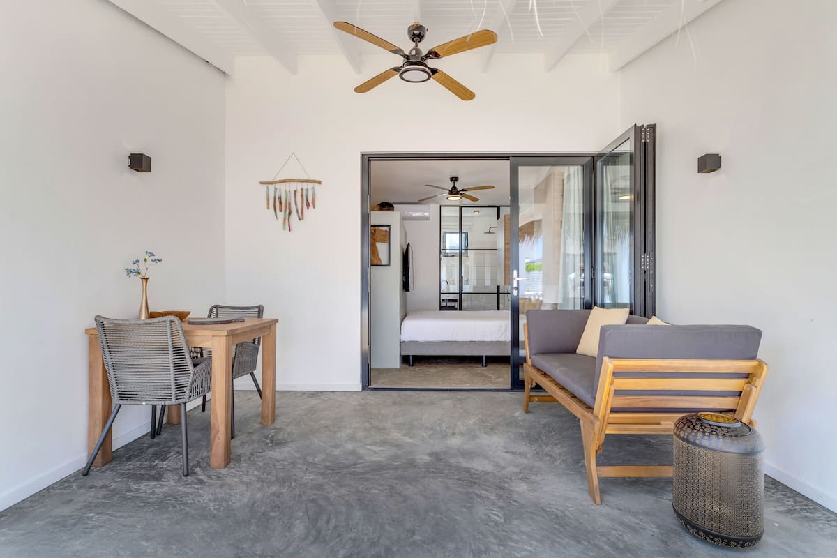 A modern room with a ceiling fan, a dining table with chairs, a sofa, and a small side table.