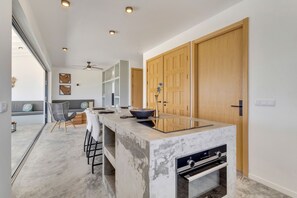 A modern kitchen with a marble island, built-in oven, and wooden cabinets.