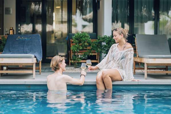 Two people sitting by a poolside, holding wine glasses. - Belnem House Bonaire (Kralendijk)