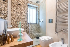 Une salle de bain moderne avec un grand lavabo, une douche à parois de verre et des toilettes.