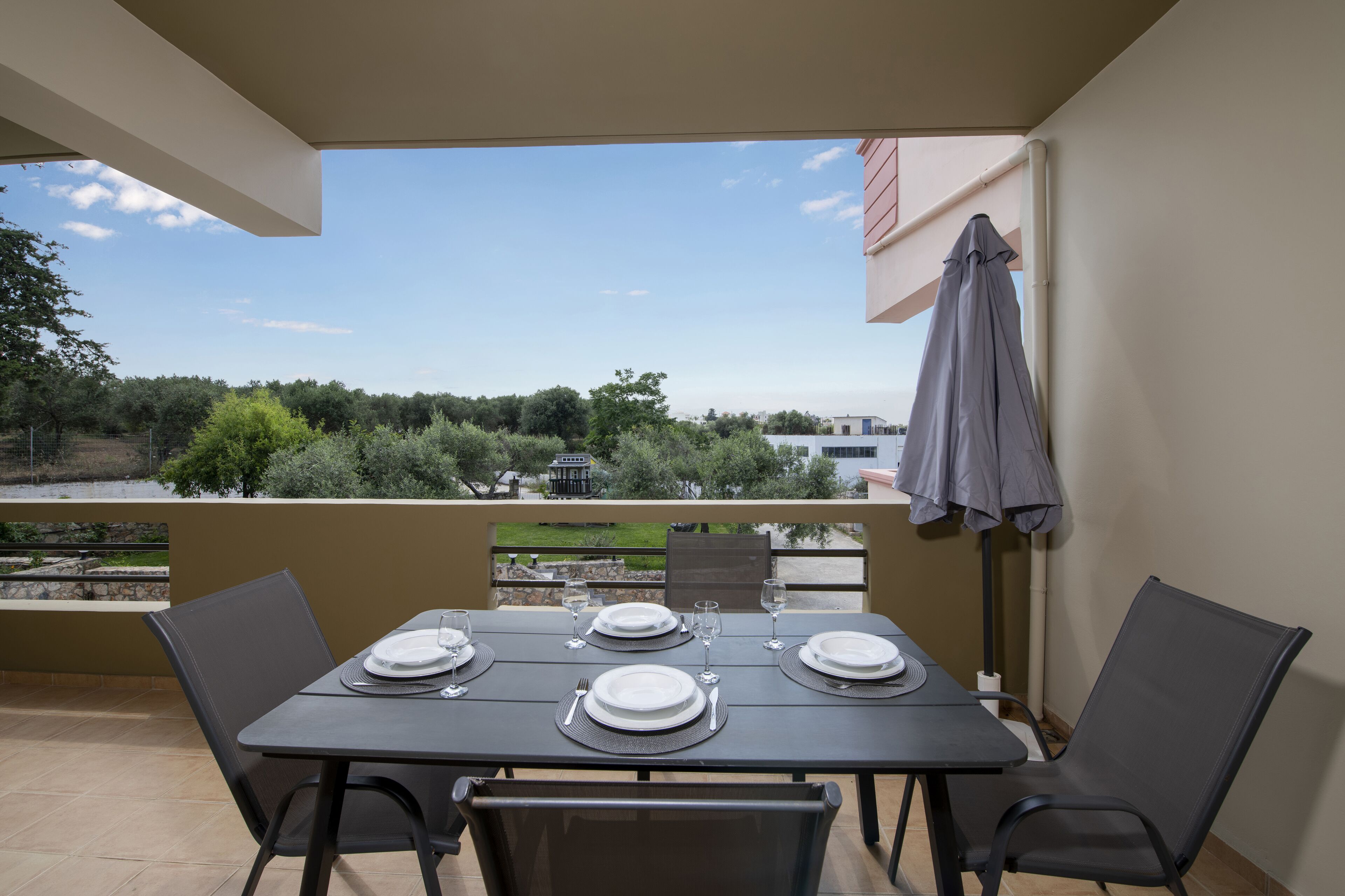 Ein Balkon mit Tisch für zwei Personen, mit Blick auf eine malerische Landschaft aus Bäumen und Gebäuden.